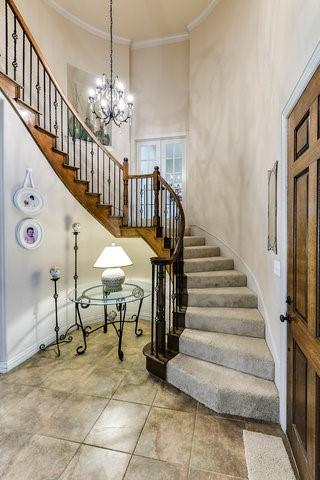 stairway with crown molding, a towering ceiling, and a chandelier