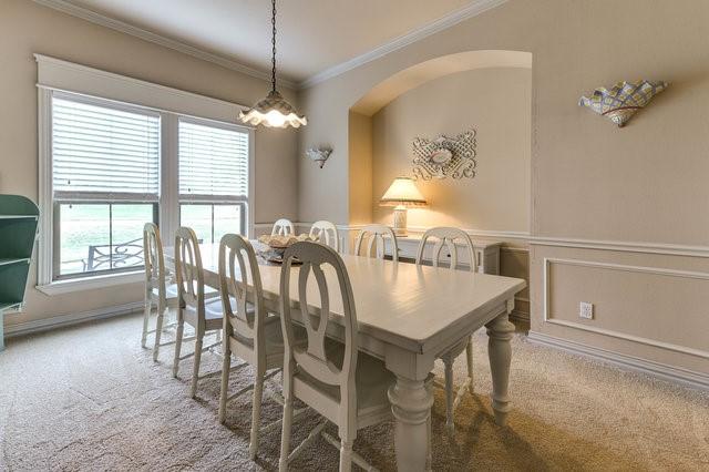 carpeted dining room with ornamental molding and a chandelier