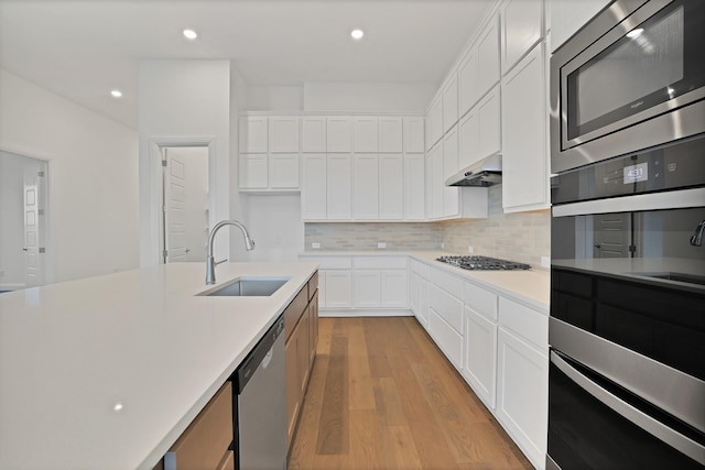 kitchen featuring sink, white cabinetry, tasteful backsplash, light hardwood / wood-style flooring, and stainless steel appliances