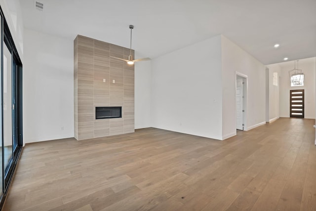 unfurnished living room featuring a tiled fireplace and light hardwood / wood-style floors