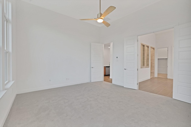 unfurnished bedroom featuring light carpet, high vaulted ceiling, ceiling fan, and ensuite bathroom