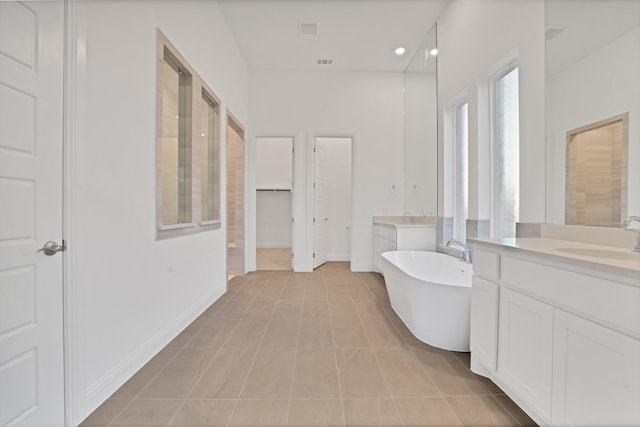 bathroom featuring vanity, a bath, and tile patterned floors