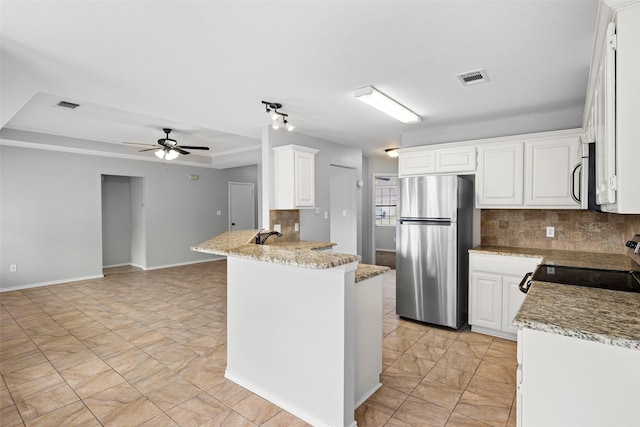 kitchen featuring kitchen peninsula, appliances with stainless steel finishes, white cabinetry, and light stone counters