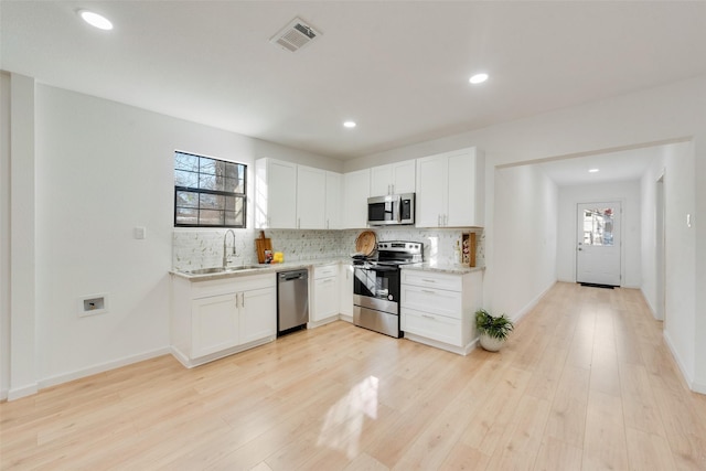 kitchen featuring tasteful backsplash, light hardwood / wood-style floors, sink, appliances with stainless steel finishes, and white cabinets