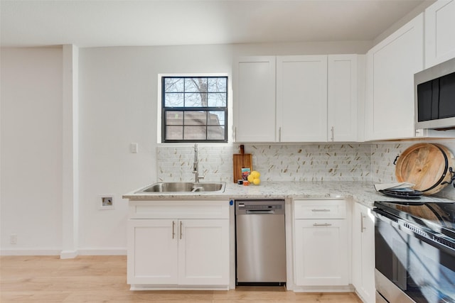 kitchen featuring white cabinetry, stainless steel appliances, backsplash, light stone counters, and sink