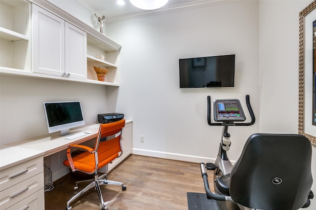 office featuring crown molding, built in desk, and light wood-type flooring