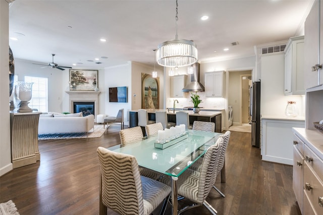 dining space with crown molding, washer / dryer, ceiling fan, and dark hardwood / wood-style flooring