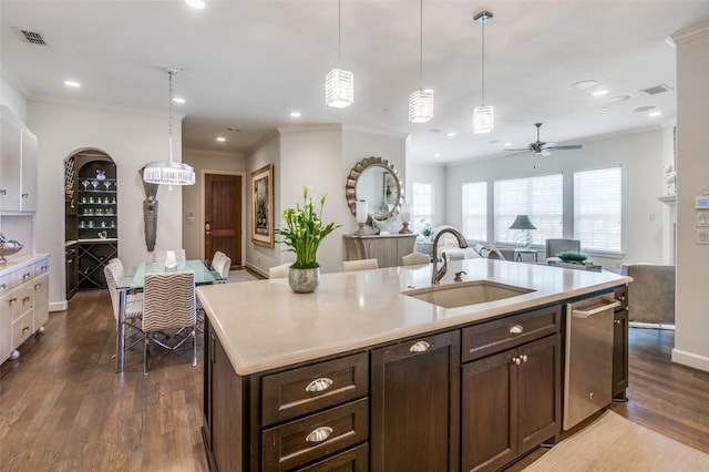 kitchen with dark brown cabinetry, a kitchen island with sink, sink, and hanging light fixtures