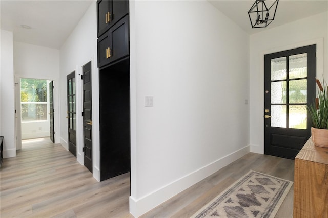 entryway with a notable chandelier, a healthy amount of sunlight, and light wood-type flooring