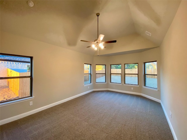 spare room featuring lofted ceiling, dark carpet, and ceiling fan