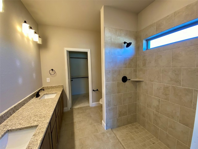 bathroom featuring toilet, a tile shower, tile patterned floors, and vanity