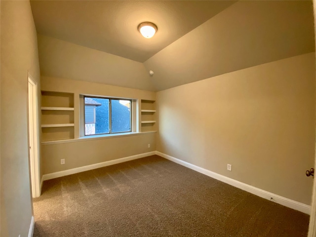 carpeted spare room featuring built in features and vaulted ceiling