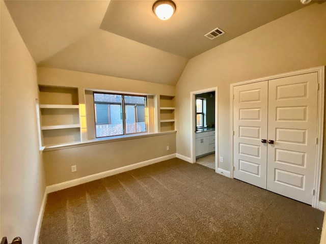 unfurnished bedroom with connected bathroom, a closet, carpet, and lofted ceiling