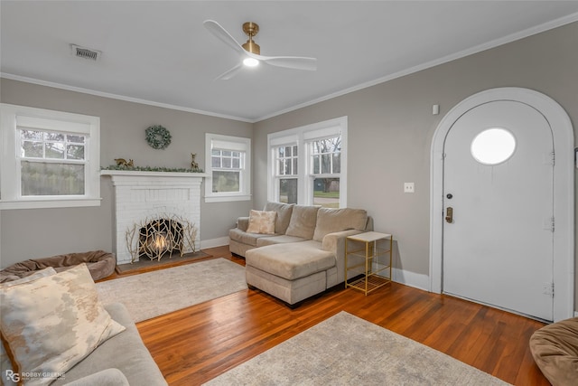 living room featuring ornamental molding, a brick fireplace, hardwood / wood-style floors, and ceiling fan