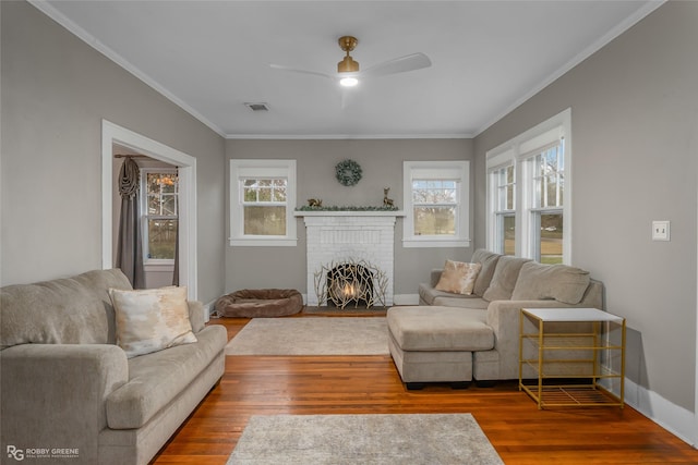 living room featuring crown molding, a healthy amount of sunlight, hardwood / wood-style floors, and a fireplace