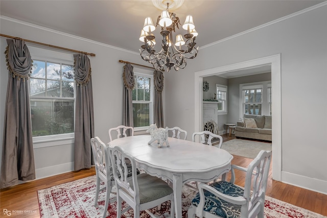 dining area with crown molding, a wealth of natural light, light hardwood / wood-style floors, and a chandelier