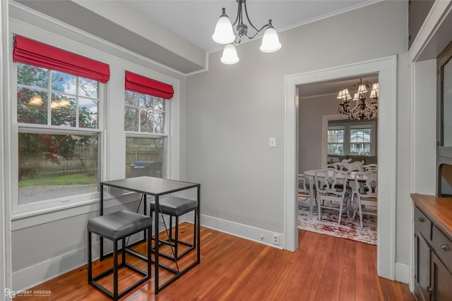 dining space with a notable chandelier, ornamental molding, and hardwood / wood-style floors