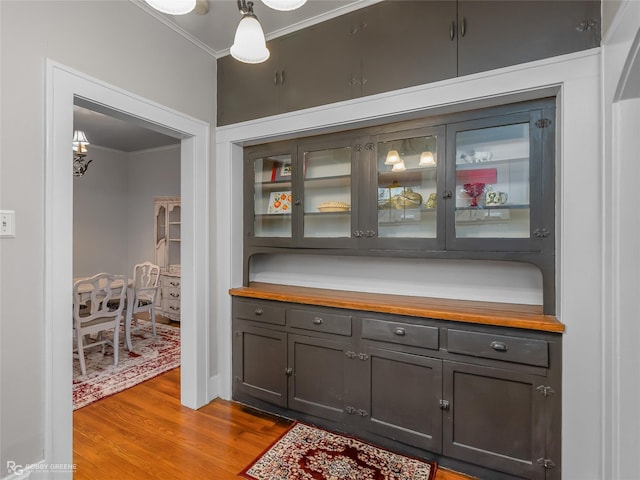 bar with crown molding, pendant lighting, butcher block countertops, and light hardwood / wood-style floors