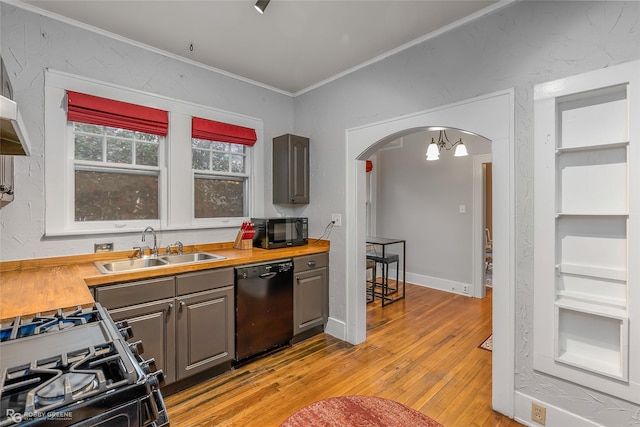 kitchen with butcher block countertops, sink, ornamental molding, black appliances, and light hardwood / wood-style flooring