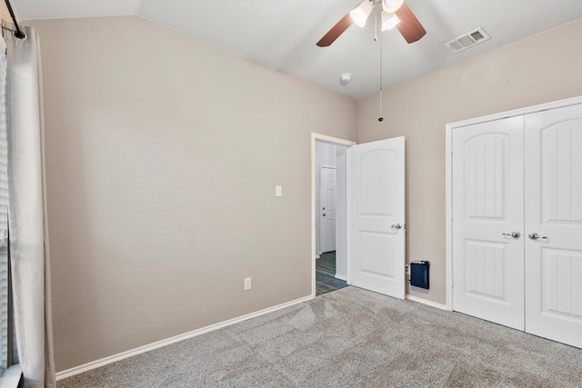 unfurnished bedroom featuring carpet, a closet, vaulted ceiling, and ceiling fan