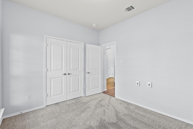 unfurnished bedroom featuring light carpet and a closet