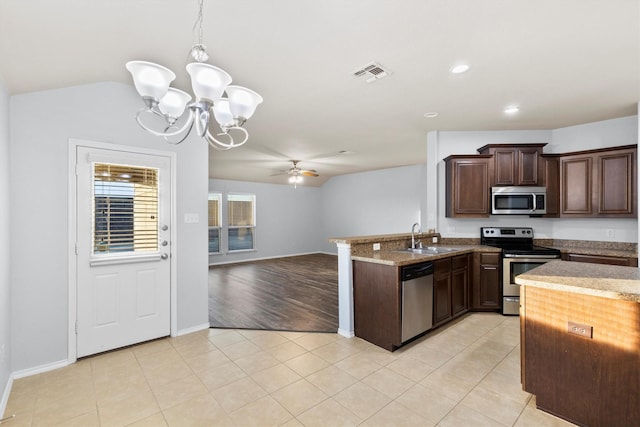 kitchen with pendant lighting, ceiling fan with notable chandelier, sink, dark brown cabinets, and stainless steel appliances