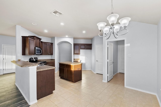 kitchen with appliances with stainless steel finishes, light stone counters, pendant lighting, an inviting chandelier, and a center island