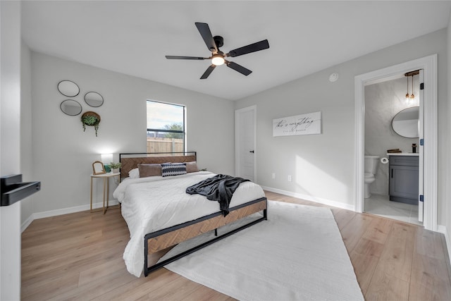 bedroom featuring ceiling fan, light hardwood / wood-style floors, and connected bathroom