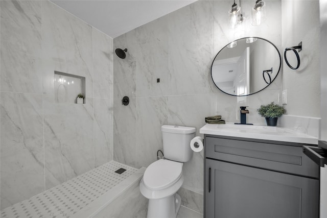 bathroom featuring a tile shower, vanity, toilet, and tile walls