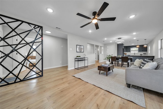 living room with ceiling fan and light hardwood / wood-style flooring