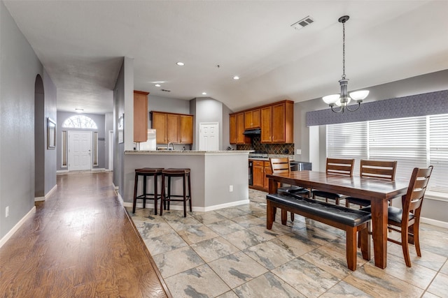 dining space featuring lofted ceiling, a notable chandelier, and sink