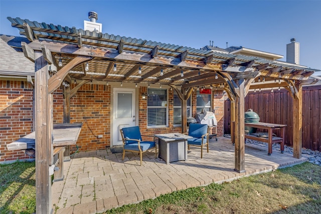 view of patio with grilling area, a pergola, and a fire pit