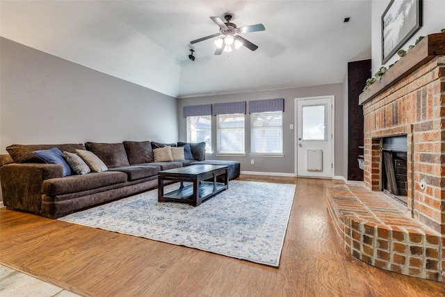 living room with lofted ceiling, hardwood / wood-style floors, a brick fireplace, and ceiling fan