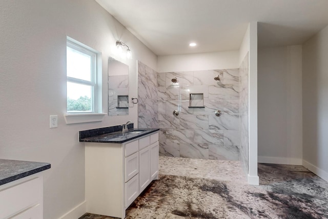 bathroom with a tile shower and vanity