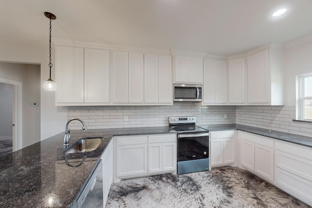 kitchen featuring dark stone counters, sink, appliances with stainless steel finishes, decorative light fixtures, and white cabinetry