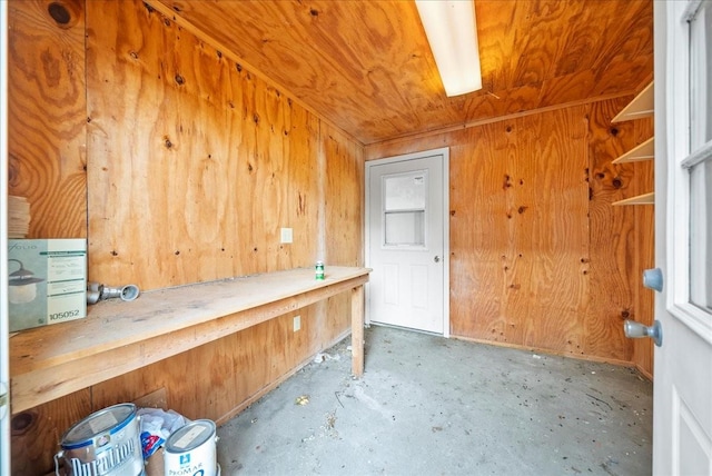 misc room featuring concrete flooring, wooden walls, and wood ceiling