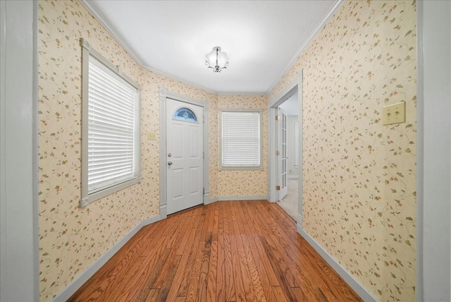 corridor featuring a healthy amount of sunlight, hardwood / wood-style flooring, and crown molding