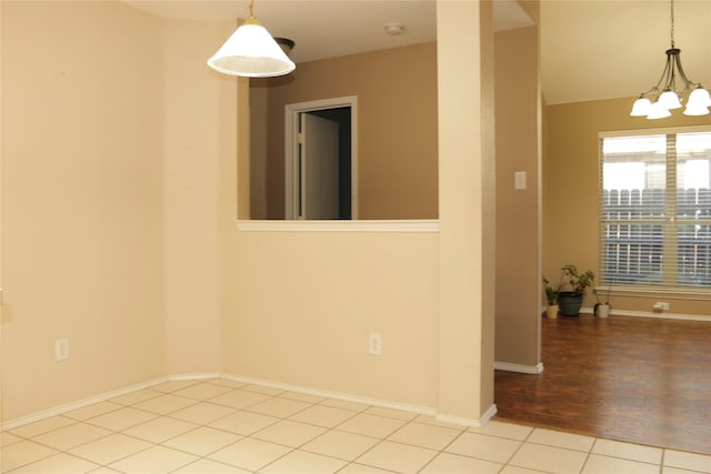 tiled spare room with a notable chandelier