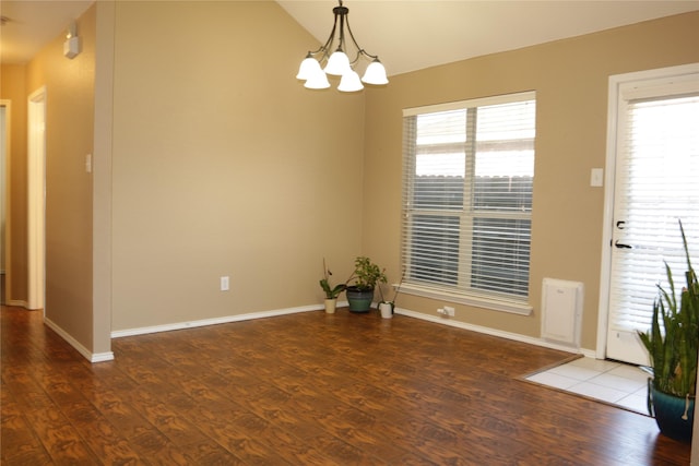 empty room featuring vaulted ceiling, dark hardwood / wood-style floors, and a notable chandelier