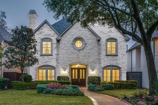 french country inspired facade featuring a yard and french doors