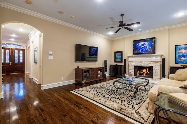 living room featuring crown molding, a fireplace, dark hardwood / wood-style flooring, and ceiling fan