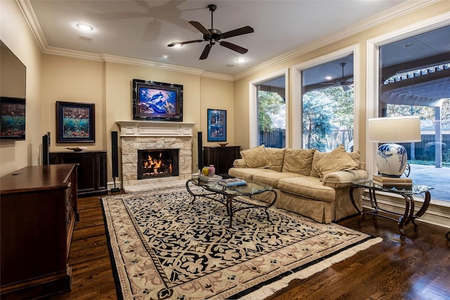 living room with ornamental molding, a stone fireplace, dark hardwood / wood-style floors, and ceiling fan