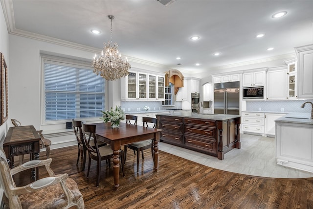 dining area with crown molding, light hardwood / wood-style floors, and sink