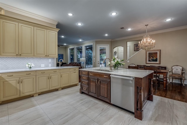 kitchen with an island with sink, sink, hanging light fixtures, stainless steel dishwasher, and cream cabinets