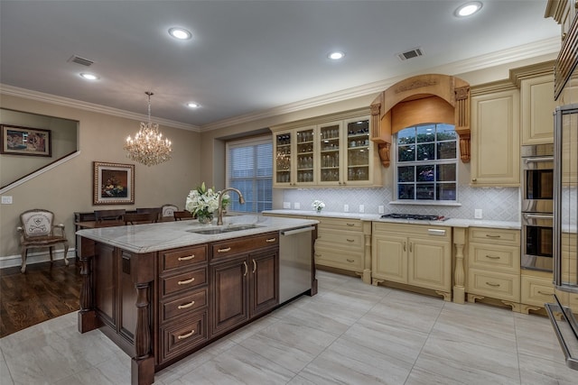 kitchen featuring appliances with stainless steel finishes, decorative light fixtures, sink, a kitchen island with sink, and light stone counters