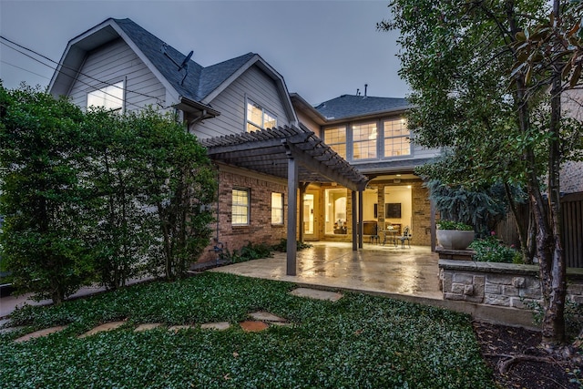 back house at dusk with a pergola and a patio area