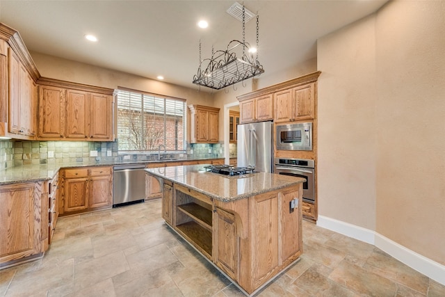 kitchen featuring light stone countertops, sink, stainless steel appliances, backsplash, and a kitchen island