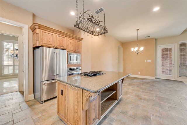 kitchen featuring a center island, hanging light fixtures, light stone countertops, stainless steel appliances, and a chandelier