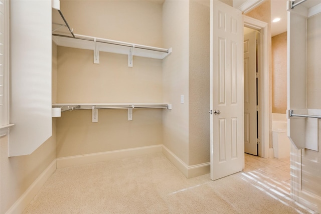 walk in closet featuring light carpet