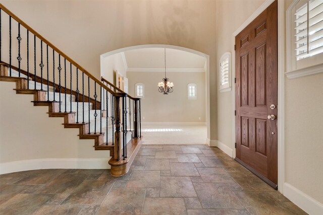 entryway with crown molding and an inviting chandelier